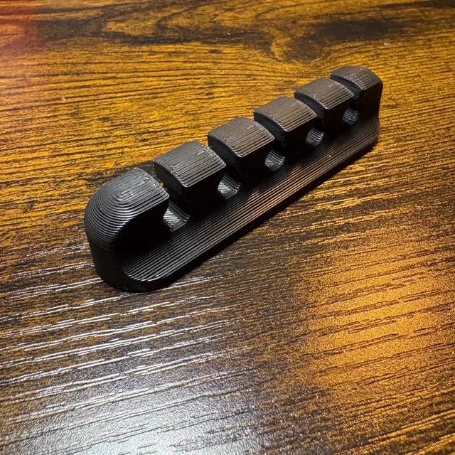 Black five slot cable organizer with a layered print texture