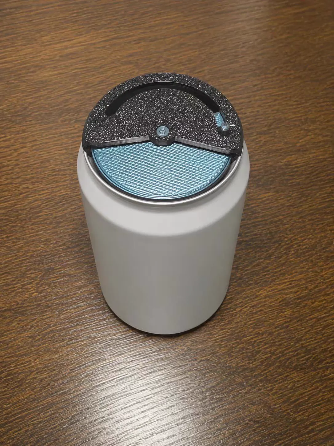 A printed lid with a teal slide fitted on a white can
